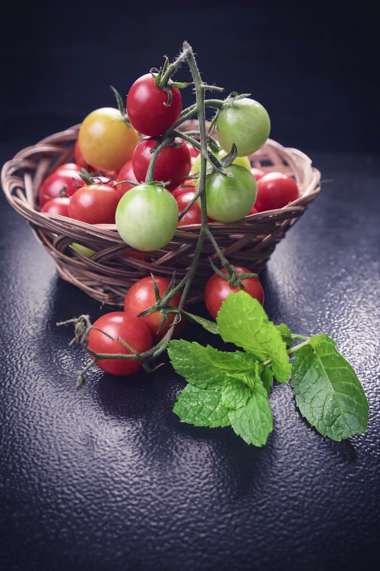 Vibrant cherry tomatoes in a wicker basket with fresh mint leaves, depicting a healthy lifestyle.